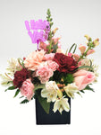 Lindo arreglo floral tamaño "petite" compuesto por rosas y claveles en tonos rosa. Es el diseño ideal combinarlo con otras sorpresas!  ESPECIFICACIONES DEL ARREGLO:  Follaje Cubo de madera Incluye dedicatoria Altura promedio del arreglo: 30 cm