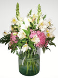 Delicado arreglo floral compuesto por delicadas rosas blancas, lirios y boca de dragón, con toques de follaje en color rosa para dar un efecto de delicadeza y elegancia. Recomendado para enviar un mensaje de sinceridad y amistad!. Especificaciones del Arreglo: Follaje. Cilindro de cristal. Mensaje impreso. Altura promedio del arreglo: 40 - 45 cm.