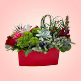 Un arreglo con un original e inesperado diseño floral, será la sorpresa perfecta para el Día de San Valentín!  ENVÍO GRATIS:  ESPECIFICACIONES DEL ARREGLO:  Arreglo en forma rectangular compuesto por rosas en intenso color rojo, originales suculentas, un discreto detalle de follaje en forma de corazón y el toque súper elegante de una increíble orquídea cultivada! Base rectangular color roja Incluye tarjeta para dedicatoria Altura aproximada  35 cms