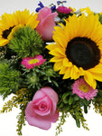 Colorido arreglo floral compuesto por girasoles, rosas, margaritas y en una increíble base metálica ovalada, color rojo. Si desea enviar una sorpresa a tu persona especial, esta es la opción indicada!. Base metálica de forma ovalada color rojo brillante, Incluye mensaje impreso, Altura promedio del arreglo: 30 cm