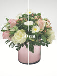 Coqueto arreglo floral compuesto por hermosas rosas, en tonos rosa y blanco acompañadas por margaritas que logran un efecto de gran sutileza. Recomendado para demostrar un amor lleno de ternura y romanticismo.  Especificaciones del Arreglo: Follaje, Cilindro de vidrio color rosa tornasol Incluye Mensaje impreso, Altura promedio del arreglo: 30 - 35 cm.