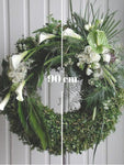 Discreto y elegante diseño de corona floral con transiciones florales y en follaje. Corona fúnebre con elegantes flores en color blanco y follaje en tonos verde sobre tripie de herrería. Altura final promedio: 1.70 cms. El tono de las flores y el follaje puede variar de acuerdo a la disponibilidad. Incluye listón personalizado.