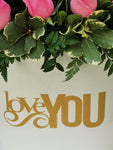 Impresionante arreglo floral compuesto por impactantes rosas en tonos rosas. Le quieres expresar tu profundo y enorme amor? Este es el regalo que nunca olvidará!Incluye tarjeta para mensaje. Especificaciones del Arreglo: Follaje, Incluye Mensaje impreso, Base metálica color blanca con diseño LOVE YOU, Altura promedio del arreglo: 55 cm