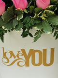 Impresionante arreglo floral compuesto por impactantes rosas en tonos rosas. Le quieres expresar tu profundo y enorme amor? Este es el regalo que nunca olvidará!Incluye tarjeta para mensaje. Especificaciones del Arreglo: Follaje, Incluye Mensaje impreso, Base metálica color blanca con diseño LOVE YOU, Altura promedio del arreglo: 55 cm
