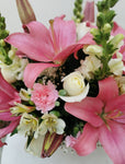 Sofisticado arreglo floral compuesto por hermosas rosas blancas, lilies rosas, lirios y boca de dragón para dar un toque de glamour y elegancia. Es una opción ideal para enviar un regalo a una persona con estilo. Base metálica color negro, Incluye mensaje impreso, Altura promedio del arreglo: 45 cm
