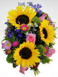 Colorido arreglo floral compuesto por girasoles, rosas, margaritas y en una increíble base metálica ovalada, color rojo. Si desea enviar una sorpresa a tu persona especial, esta es la opción indicada!. Base metálica de forma ovalada color rojo brillante, Incluye mensaje impreso, Altura promedio del arreglo: 30 cm