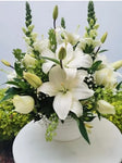 Discreto y elegante arreglo floral podrá hacer llegar como un mensaje de solidaridad a esa persona que desea acompañar. Arreglo con rosas blancas y casablancas. Sensibles a lo delicado de estos momentos; te invitamos a hacerte presente a través de este arreglo floral. Arreglo en maceta blanca de cerámica con rosas blancas, casablancas y follaje en tonos verde. Medidas aproximadas: Altura promedio: 45 cm. Ancho promedio: 38 cm. El tono de las flores puede variar de acuerdo a la disponibilidad.