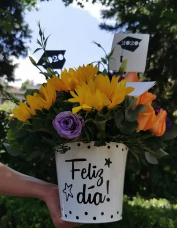 Un regalo lleno de energía y actitud positiva para sorprender al Graduado!. Hermoso arreglo floral de Girasoles y lisanthus de lindos colores que generan un increíble contraste lleno de vida. Bouquet de Girasoles con base metálica tipo cubeta con letrero feliz día!, Diseño personalizado para graduación Cubeta de Metal con personalización en vinil con la frase "Feliz Día", Mensaje impreso, Altura promedio del arreglo: 30 - 35 cm